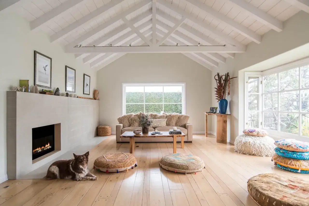 Gemütliches Wohnzimmer mit Kamin, Hund und vielen Sitzkissen. Natürliche, gesunde Baumaterialien wie Holz und Stein schaffen eine warme Atmosphäre.