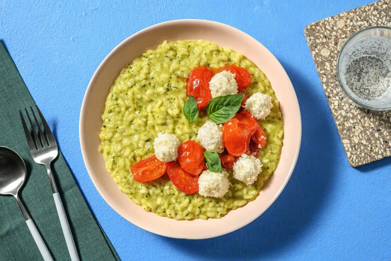Risotto con zucchine cremoso, guarnito con pomodorini confit, mozzarelline e basilico fresco. Un piatto colorato e gustoso.