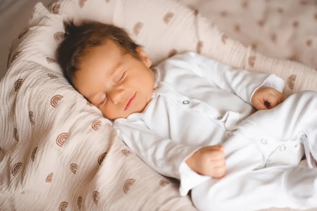 Un neonato dorme sereno, avvolto in una copertina con arcobaleni. Chissà quali mondi incantati esplorano i neonati sognano.