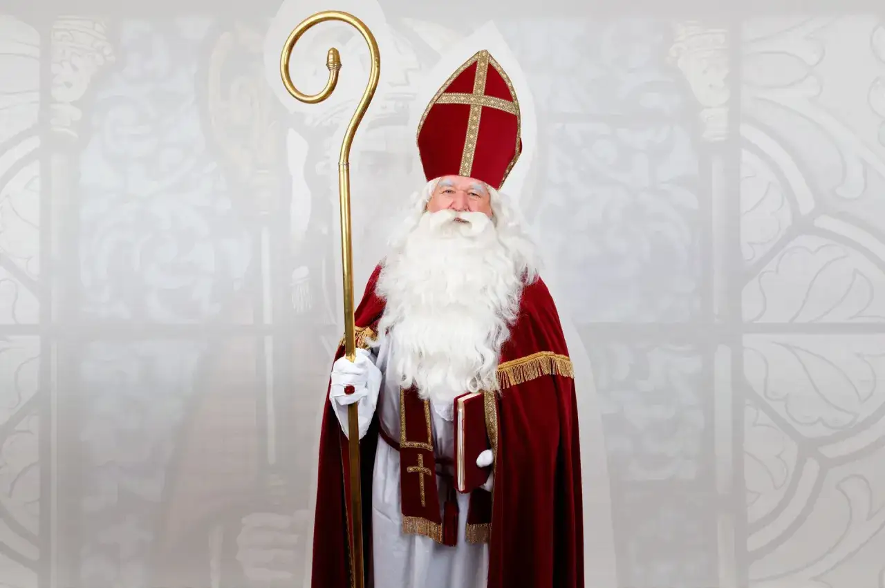 Święty Mikołaj w bogatym stroju, z pastorałem i księgą, gotowy opowiedzieć dzieciom historię o swojej dobroci.