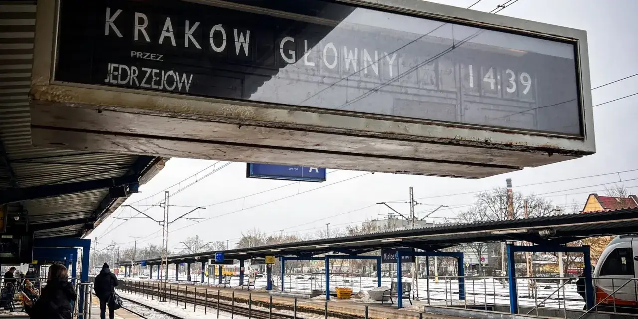 Tablica informacyjna na dworcu kolejowym: pociąg Intercity do Krakowa Głównego przez Jędrzejów odjeżdża o 14:39.
