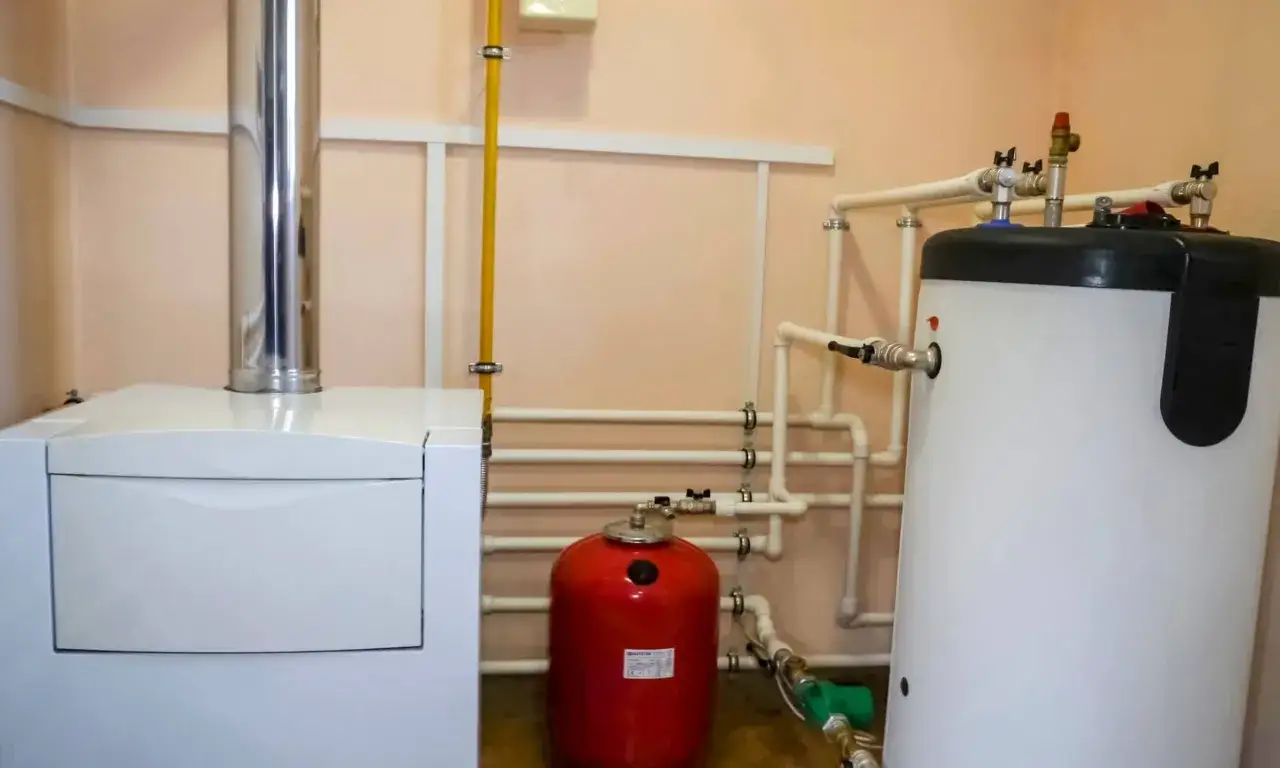 Instalaci&oacute;n de sistema de calefacci&oacute;n con caldera de gas, acumulador de agua caliente y dep&oacute;sito de expansi&oacute;n rojo.