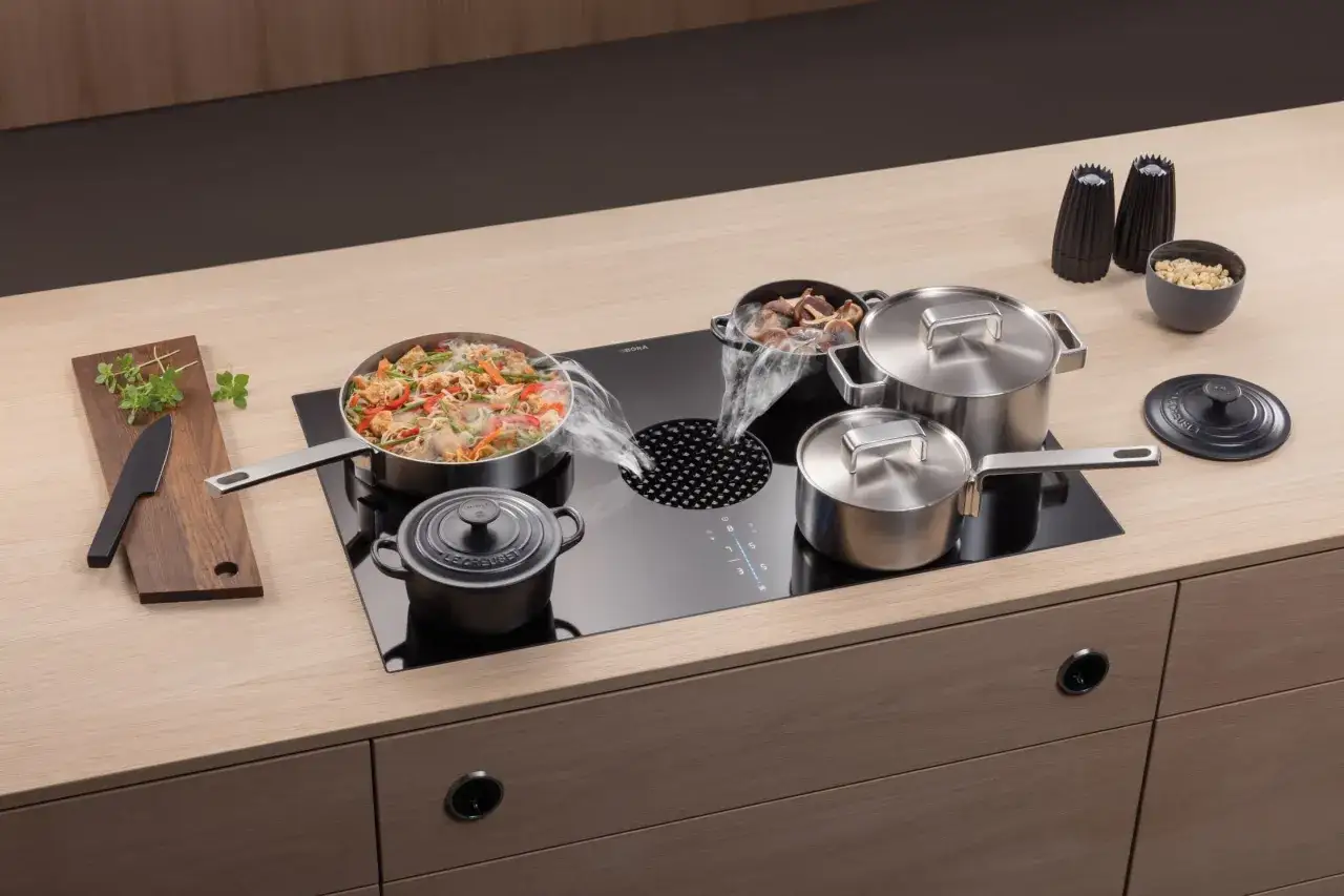 Kochen mit dem Bora Umluft-Abzug: Dampf steigt aus T&ouml;pfen auf, w&auml;hrend ein Wok mit Gem&uuml;se und Nudeln auf dem Kochfeld steht. Gute Bora Umluft Erfahrungen sind hier garantiert.