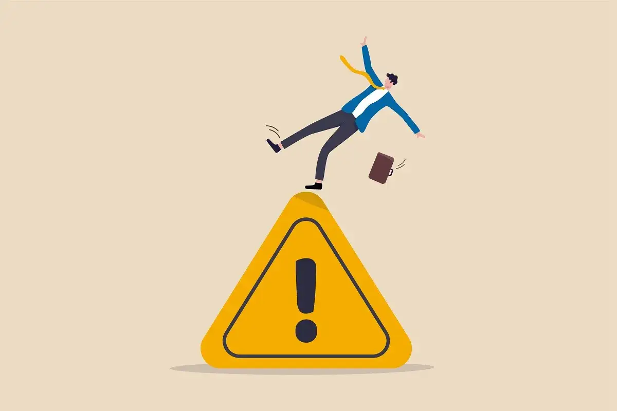 Uomo d'affari in caduta su un segnale di pericolo, un esempio di near miss per la sicurezza sul lavoro.