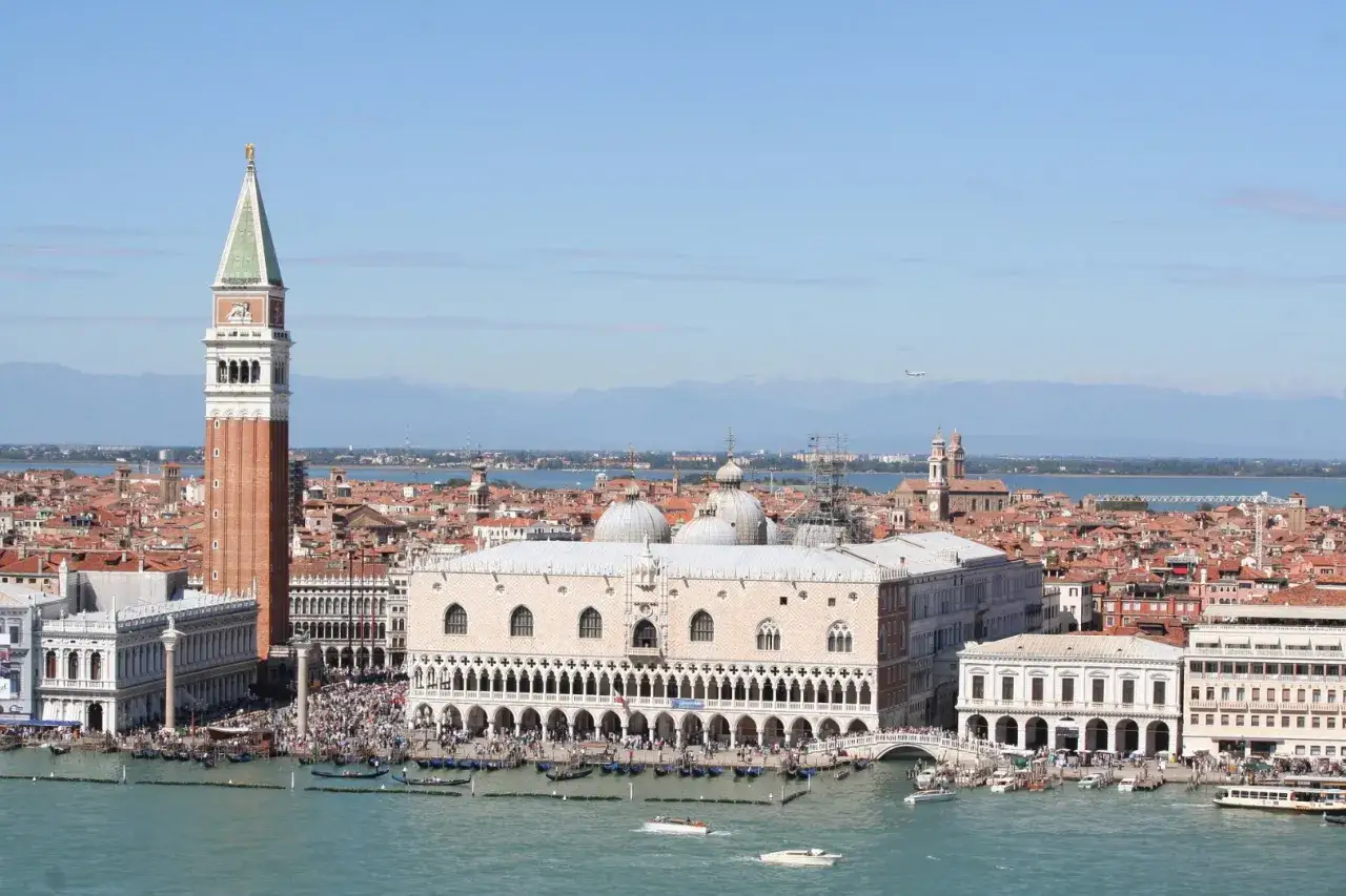 Vista panoramica di San Marco a Venezia, con il Campanile, il Palazzo Ducale e il bacino acqueo animato da gondole e vaporetti.