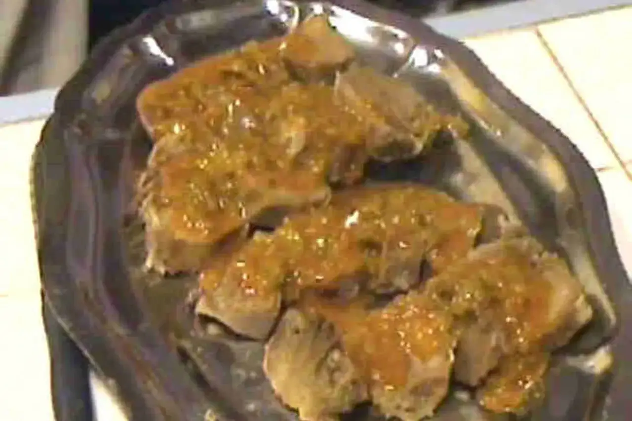 Tranches de langue de porc nappées d'une sauce savoureuse, servies sur un plat en métal.