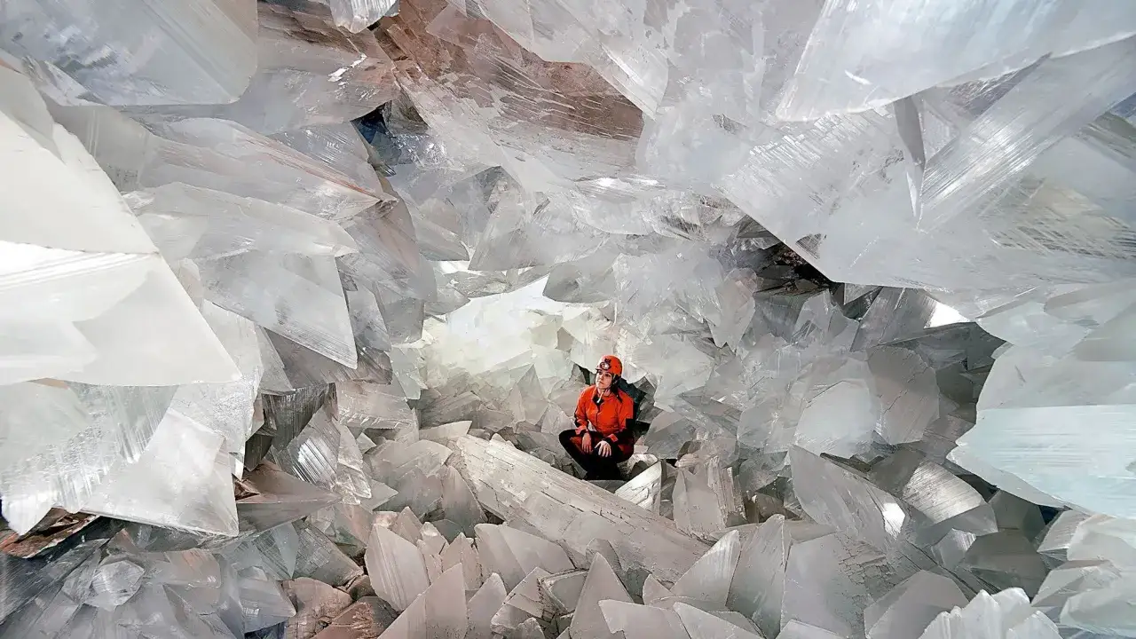 Explora la Cueva de los Cristales en Pulpí, un lugar fascinante que ver, con cristales gigantes y una persona admirando su belleza.