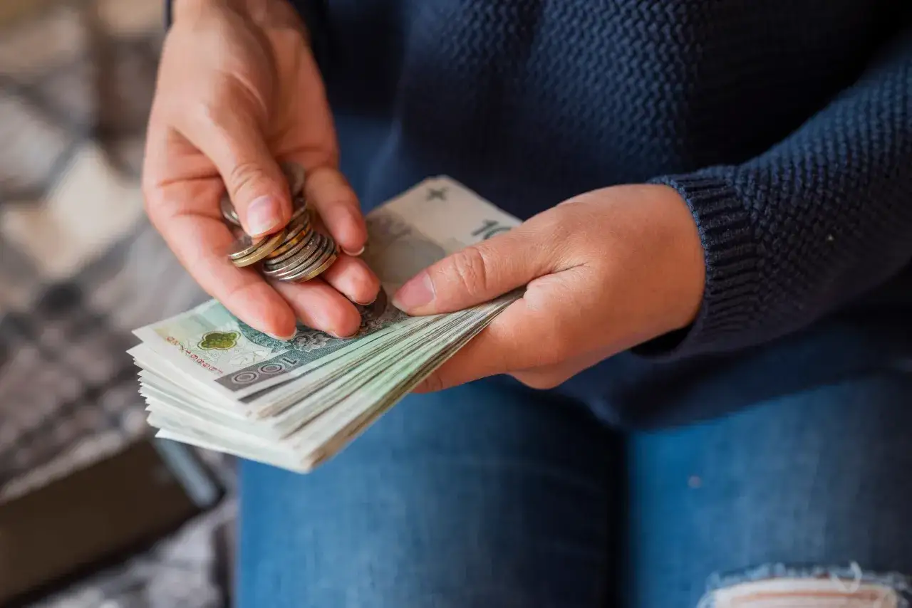 Dłonie liczą pieniądze, co może być związane z rozliczeniem umowy o dzieło, gdy pojawia się komornik.