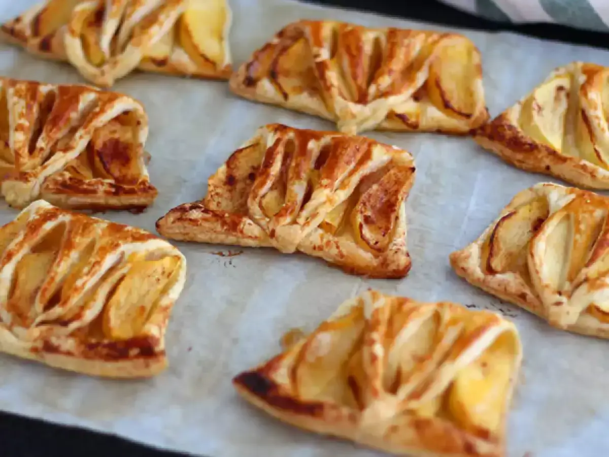 Plusieurs délicieuses pommes en pâte feuilletée dorées et croustillantes, disposées sur du papier sulfurisé.