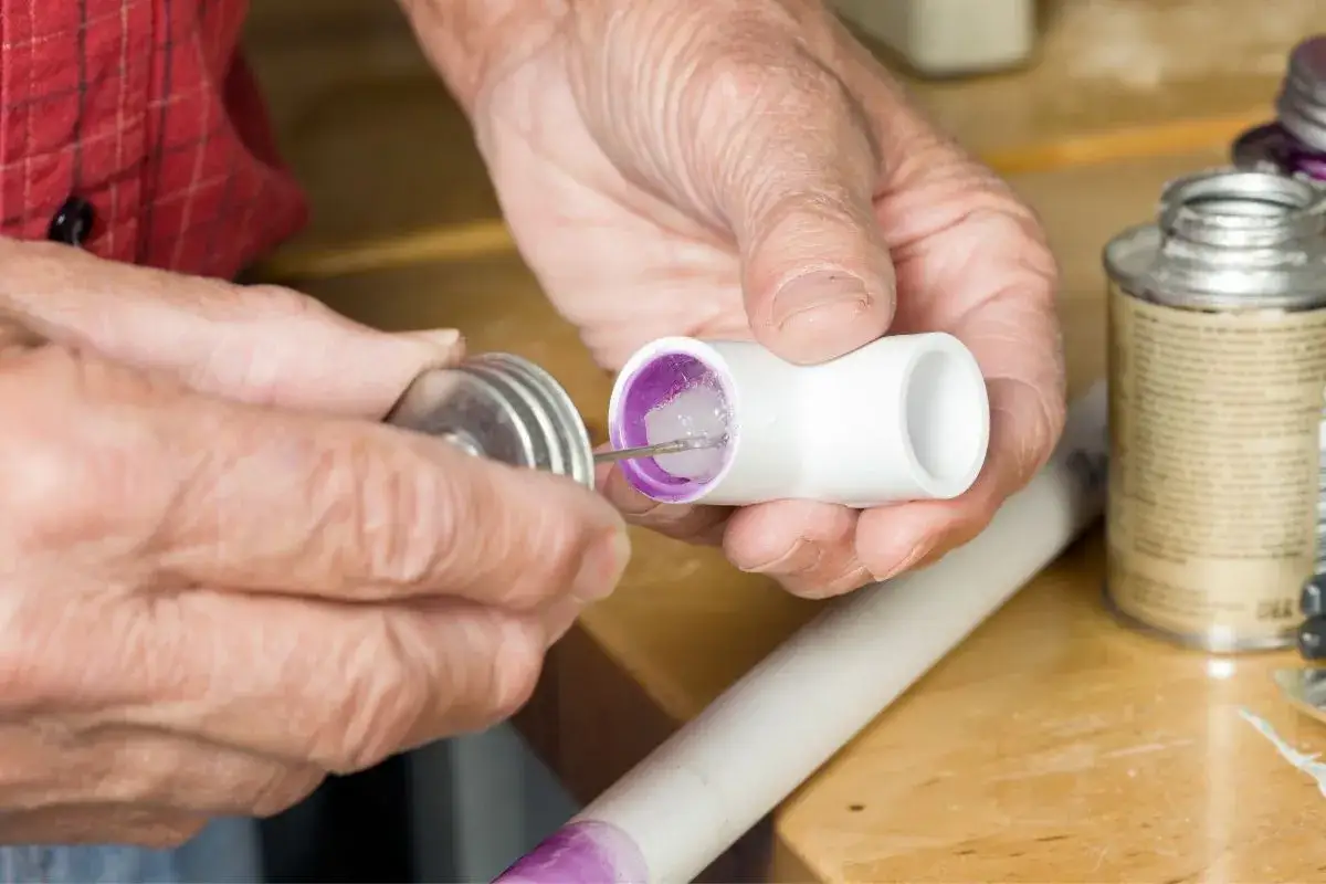 Application de colle PVC sur un raccord. Le temps de s&eacute;chage colle PVC est crucial pour une installation r&eacute;ussie.
