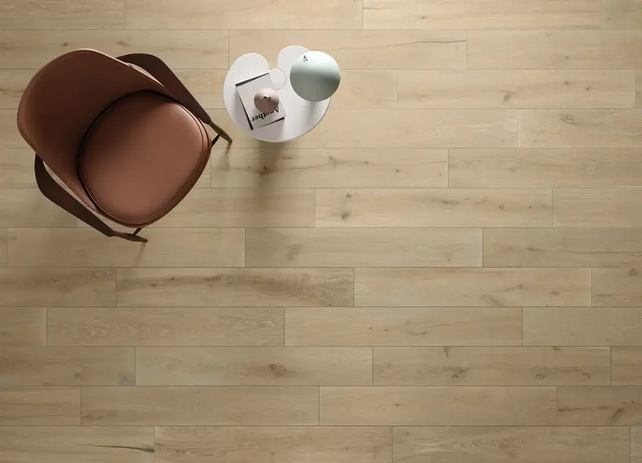 Silla marr&oacute;n y mesa auxiliar sobre suelo de **azulejos a matajunta** con acabado de madera clara.