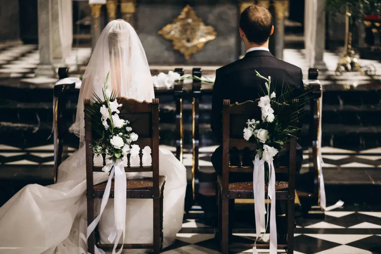 Para młoda siedzi w kościele, przygotowując się do ceremonii. Warto wiedzieć, ile ksiądz bierze za ślub, by zaplanować budżet.