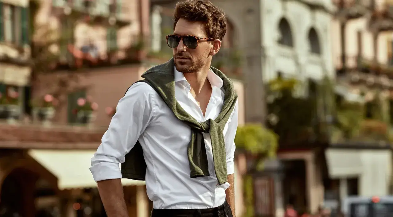 Mann mit Sonnenbrille und wei&szlig;em Hemd, Pullover &uuml;ber den Schultern, l&auml;ssiger Look in Italien.