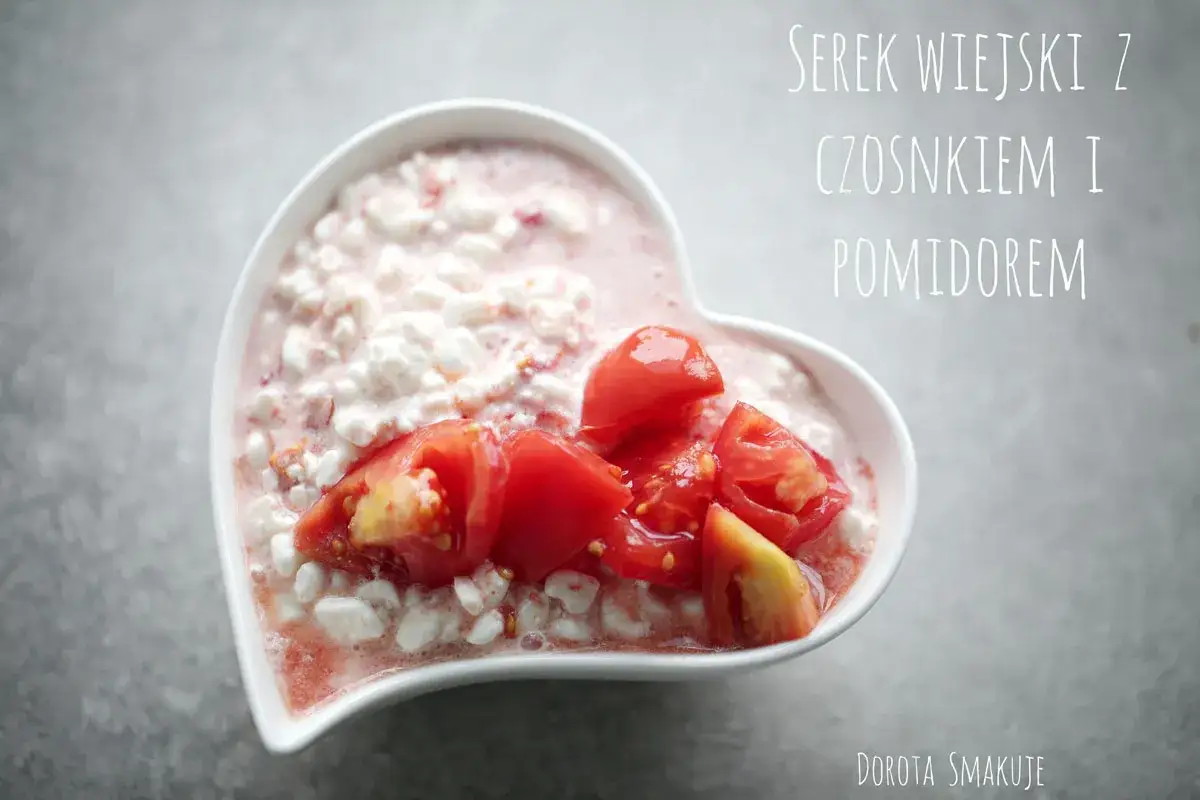 Serek wiejski z pomidorem i czosnkiem w miseczce w kształcie serca. Pyszna i zdrowa przekąska.