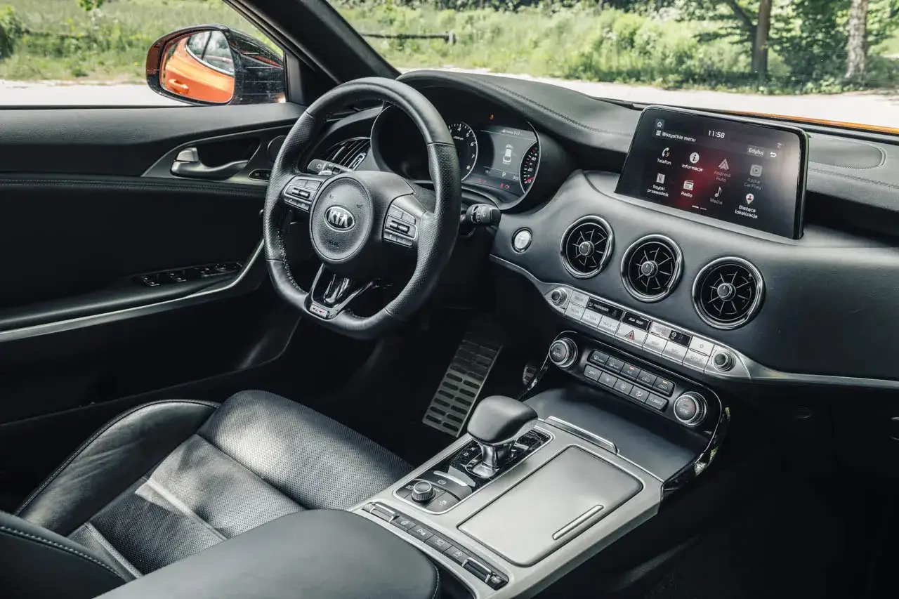 Wnętrze Kia Stinger: skórzana tapicerka, sportowa kierownica, ekran multimedialny i aluminiowe pedały.