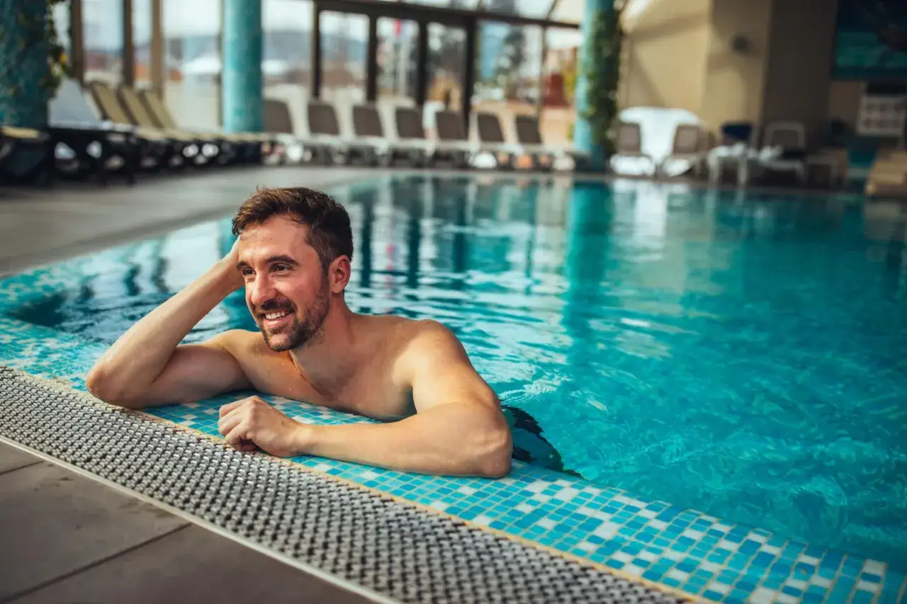 Uśmiechnięty mężczyzna relaksuje się w basenie. Idealne miejsce na odpoczynek i regenerację – takie jak termy Opole.