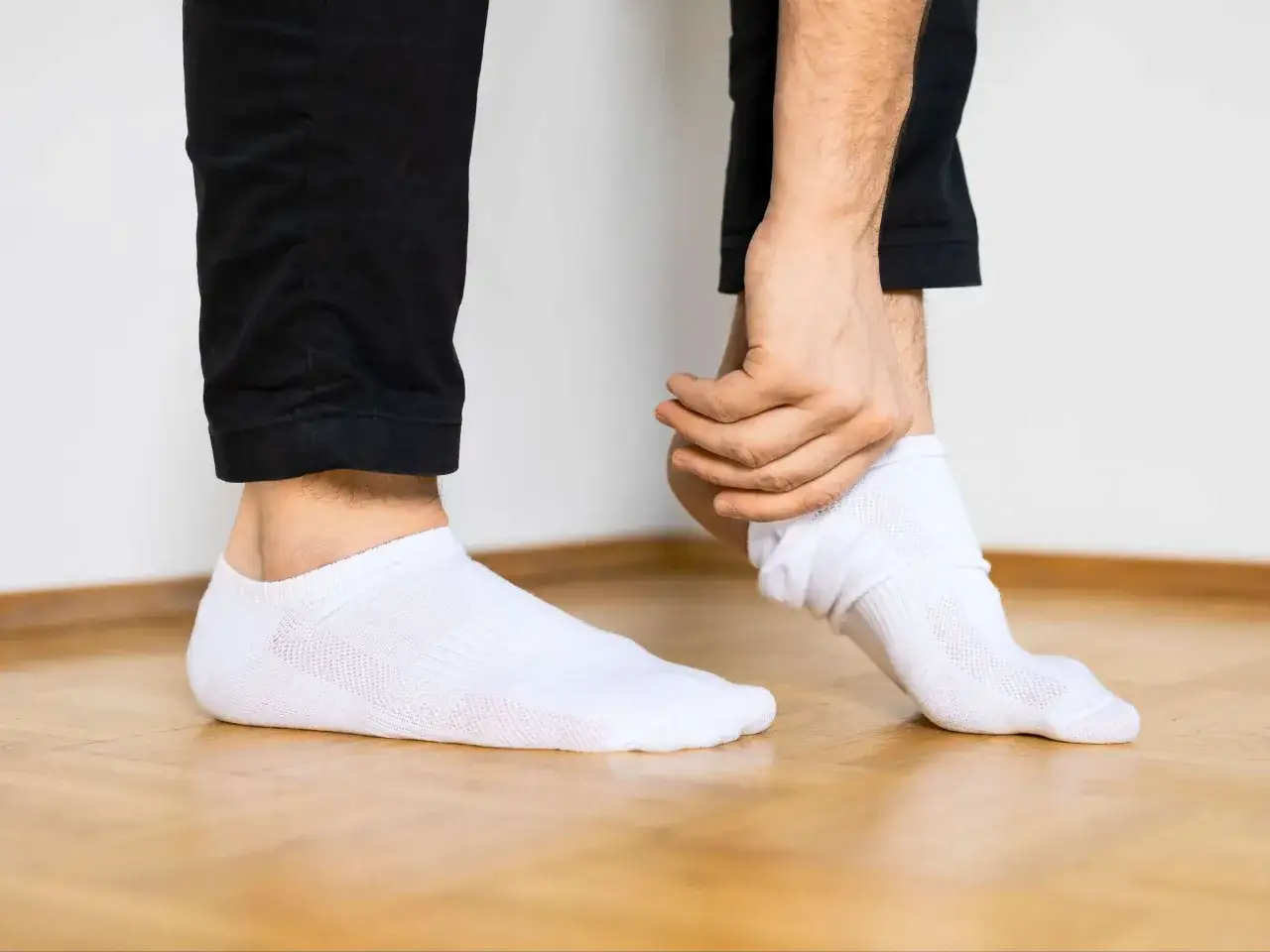 Mann zieht weiße Socken an, um sie sauber zu bekommen.