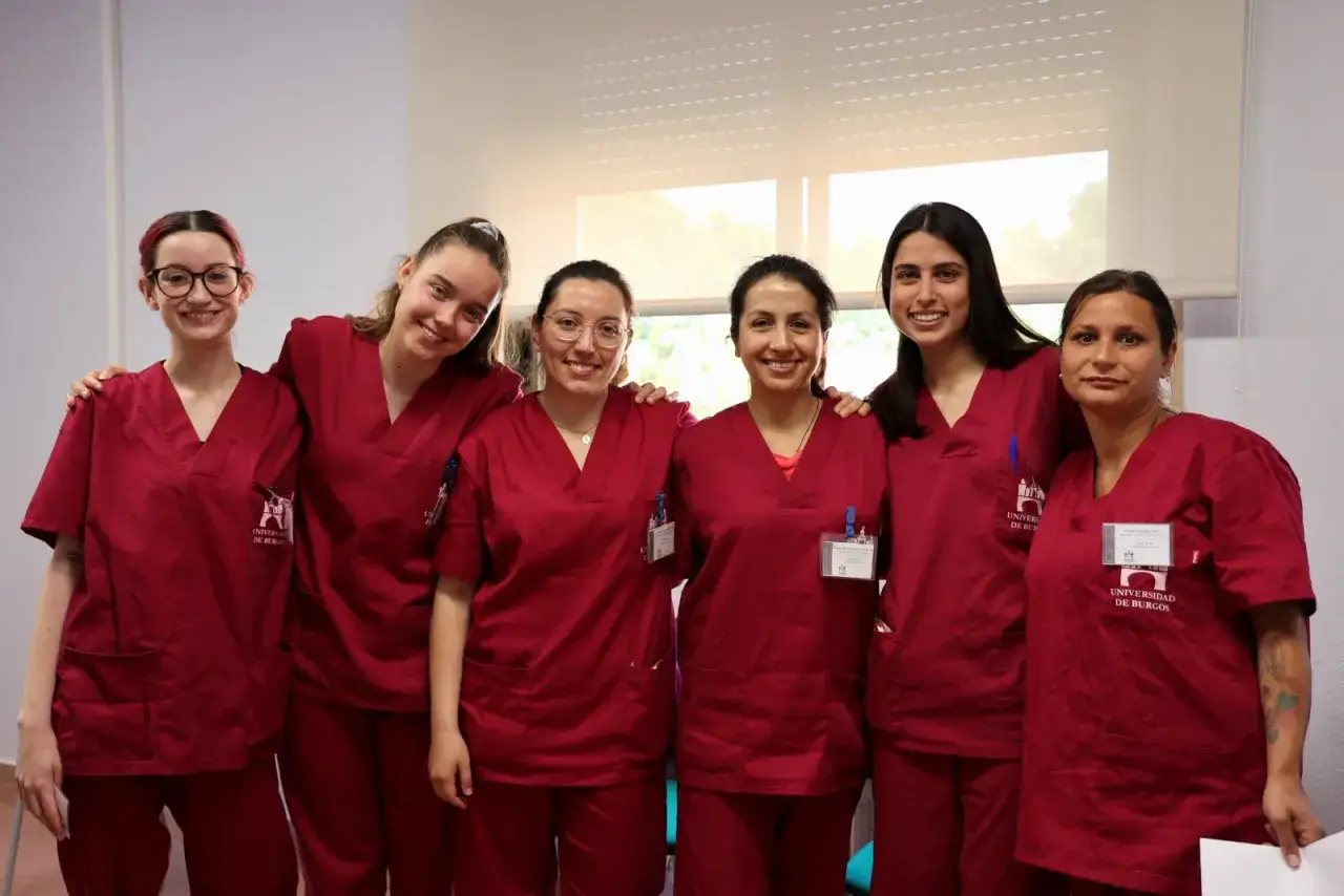 Seis estudiantes sonr&iacute;en, vestidas con uniformes de **terapia ocupacional carrera**.