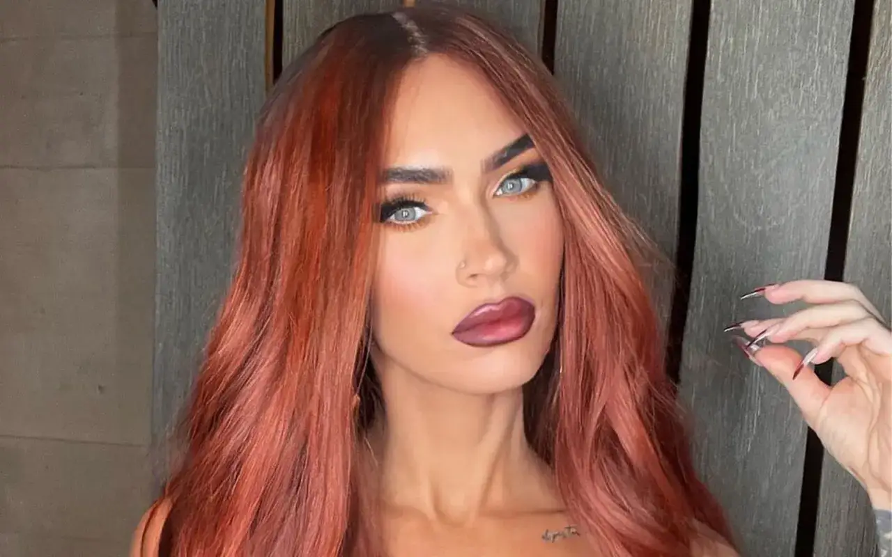 Capelli ramati e labbra scure, un look audace che evoca l'autunno armocromia. Occhi azzurri penetranti e unghie affilate completano l'immagine.