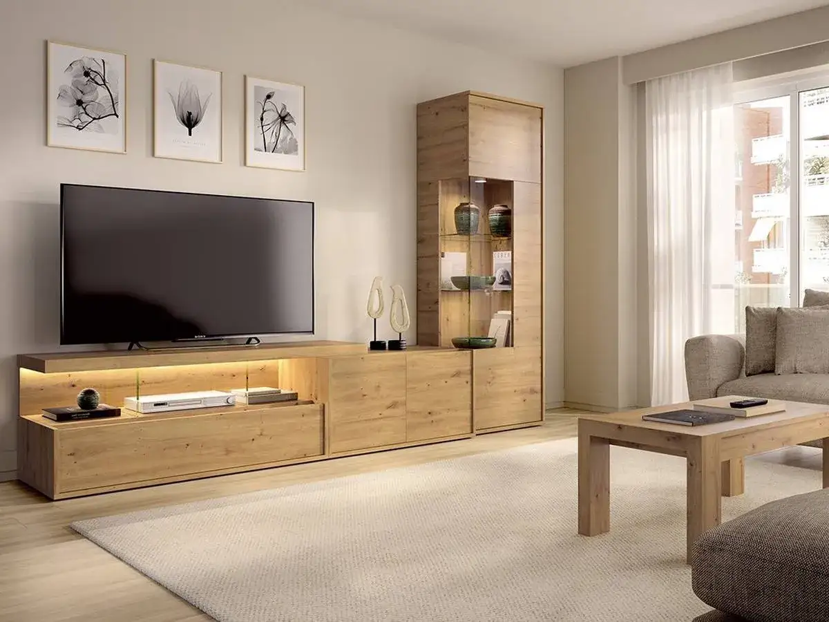 Un moderno mueble de sal&oacute;n de madera clara con una gran televisi&oacute;n para poner la tele en medio del sal&oacute;n. Tres cuadros de flores cuelgan sobre ella.
