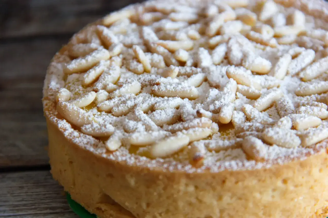 Una deliziosa torta della nonna, ricoperta di pinoli e zucchero a velo, pronta per essere gustata.