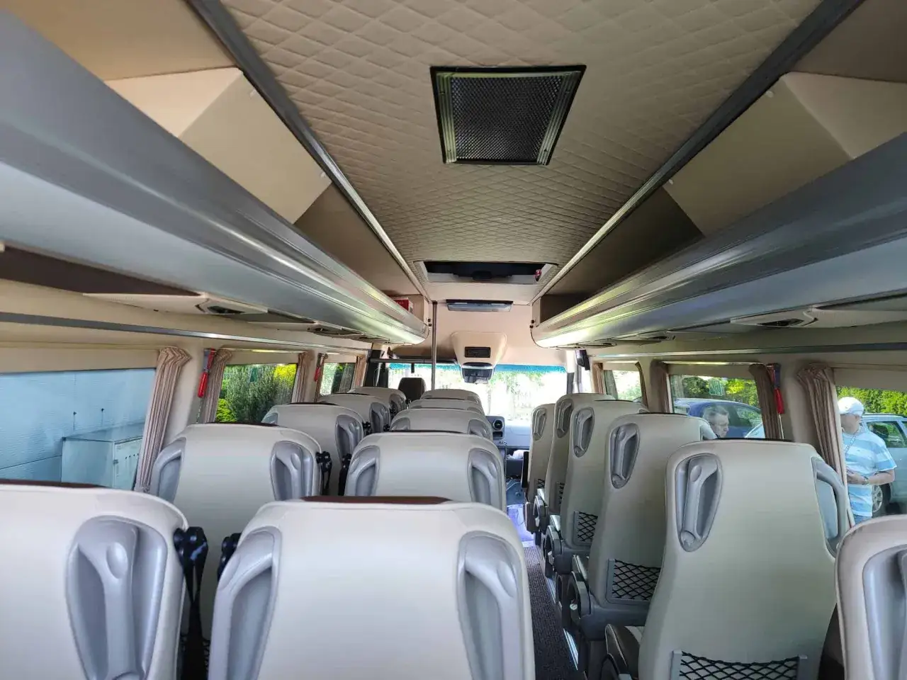 Wnętrze komfortowego busa 20 osobowego z jasnymi siedzeniami i klimatyzacją.