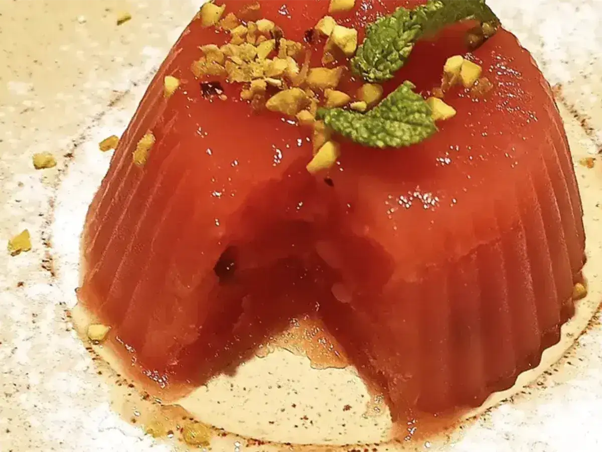 Delizioso gelo di melone rosso, guarnito con pistacchi tritati e foglioline di menta fresca. Un dolce estivo rinfrescante.