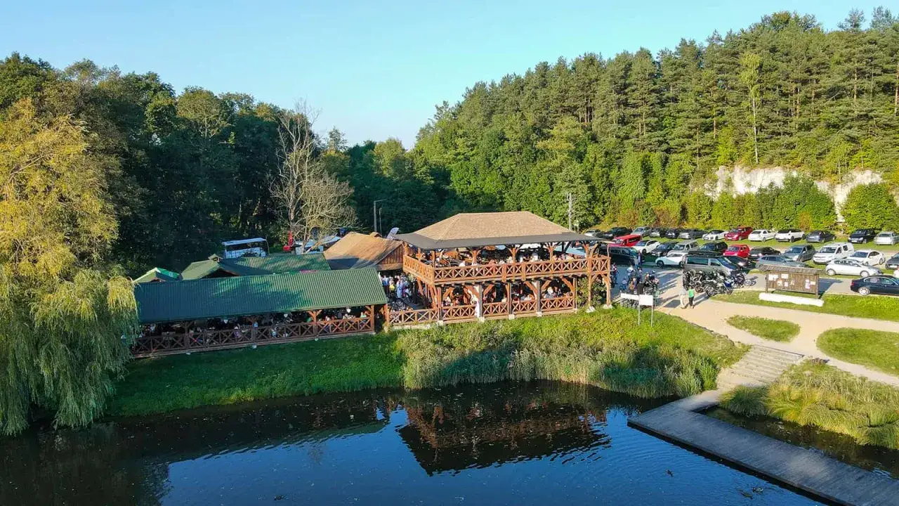 Drewniane restauracje nad potokiem grzędy, z tarasami pełnymi ludzi, otoczone lasem i parkingiem pełnym samochodów.