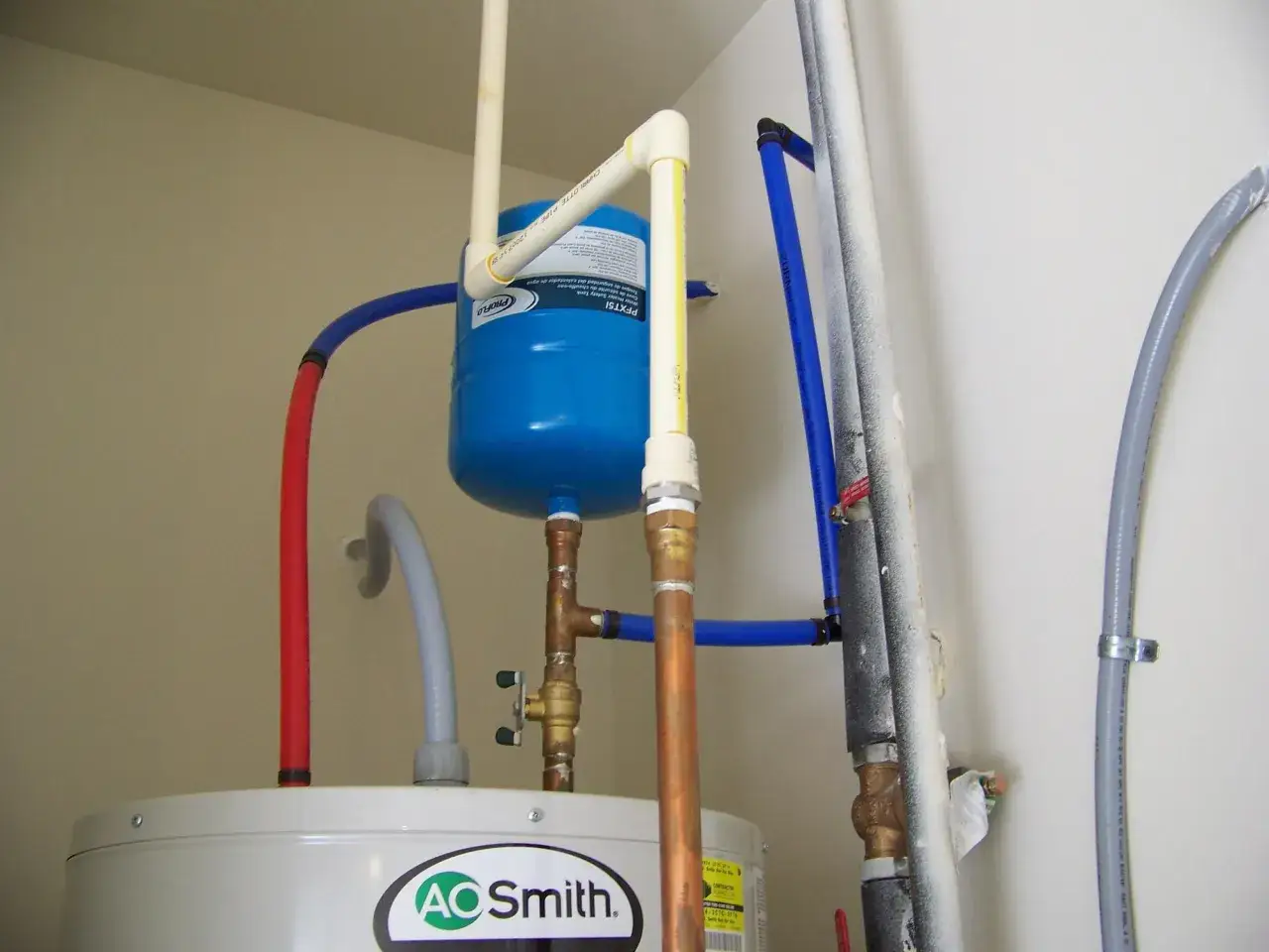 System hydrauliczny z niebieskimi rurkami PEX, zbiornikiem i bojlerem AO Smith.