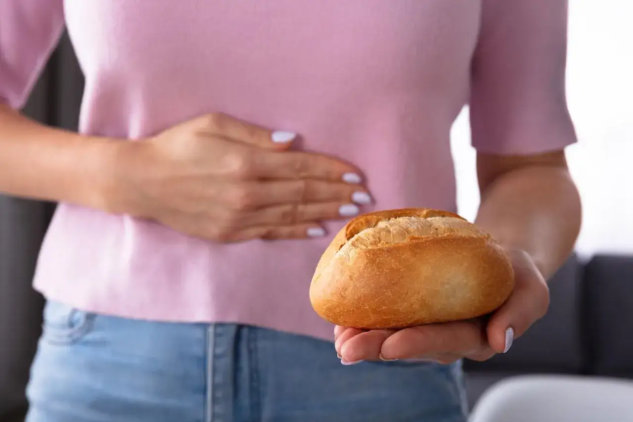 Kobieta w ciąży trzymająca brzuch, obok tabletki i chleb