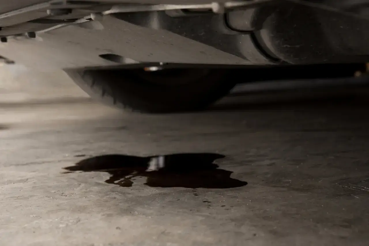 Mancha de aceite en el suelo bajo un coche. ¿Cuánto costará arreglar mi coche si pierde aceite?