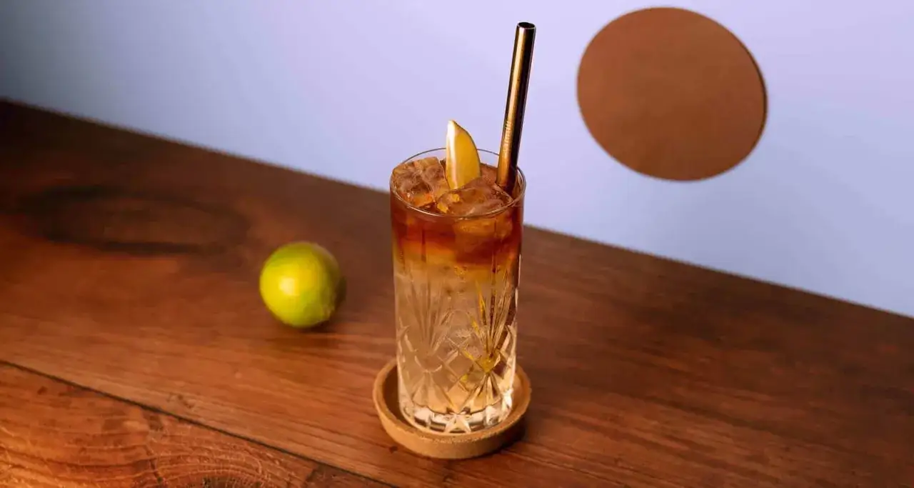 En mörk och stormig drink med is, lime och ett gyllene sugrör. En perfekt dryck för en mysig kväll.