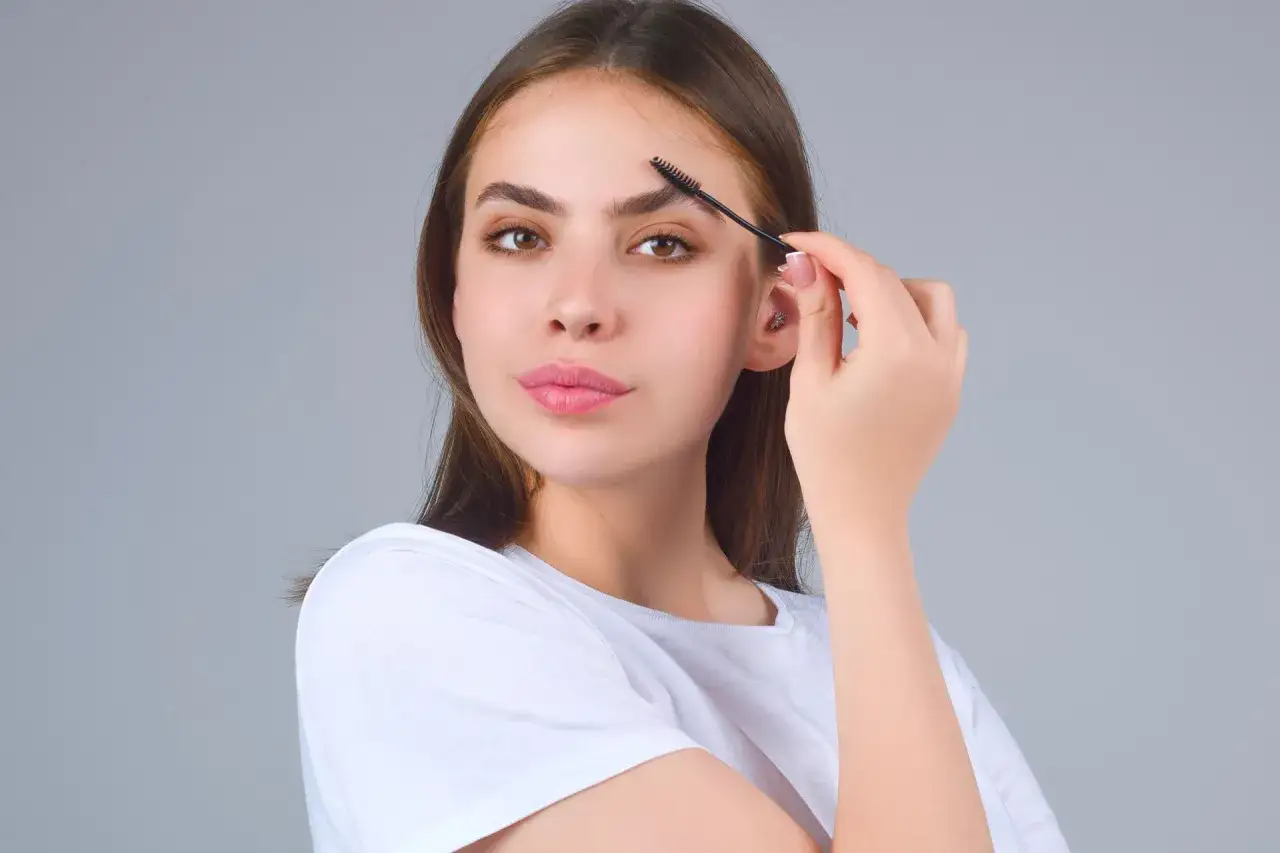 Jeune femme se brossant les sourcils. Une pr&eacute;occupation future pourrait &ecirc;tre la perte de sourcils avec l'&acirc;ge.