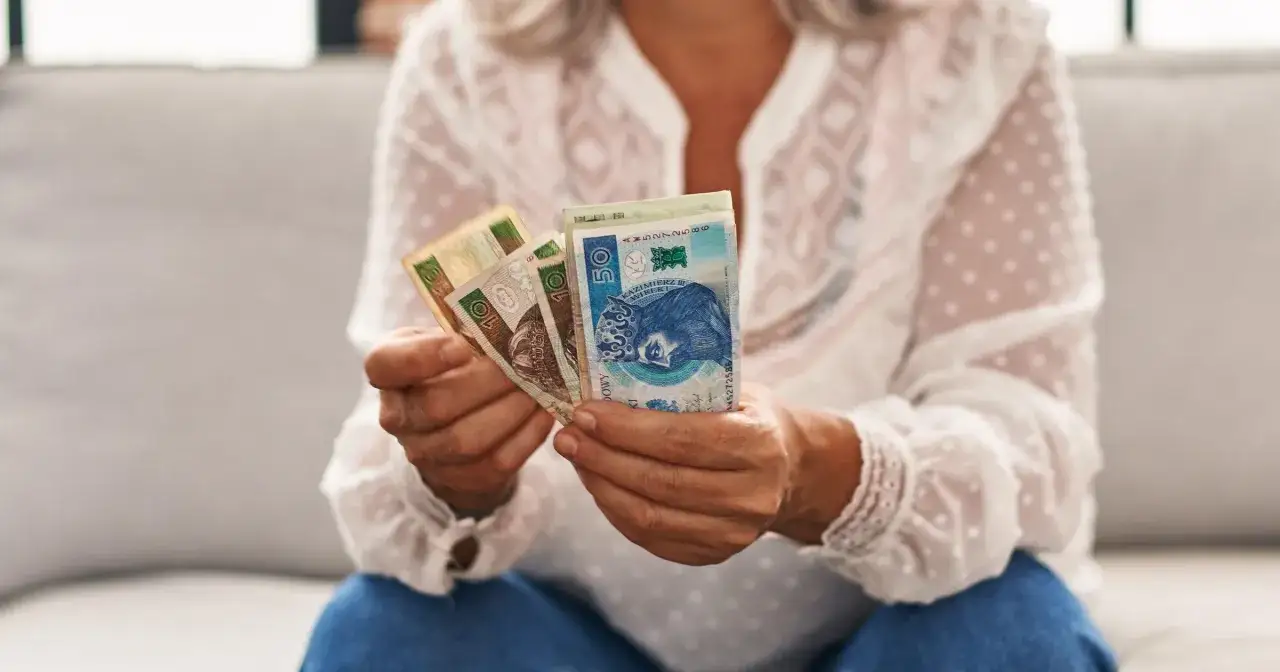 Dłoń trzyma polskie banknoty, być może to oczekiwana trzynasta emerytura.