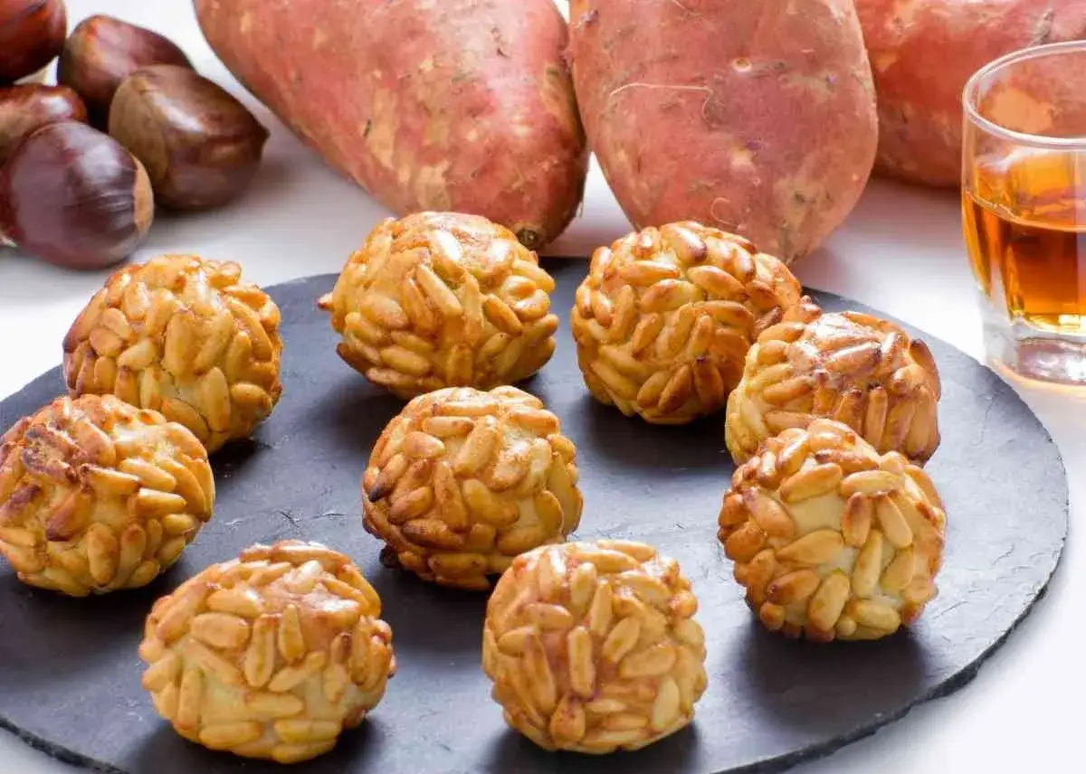 Deliciosos panellets de boniato cubiertos de piñones tostados, listos para disfrutar.