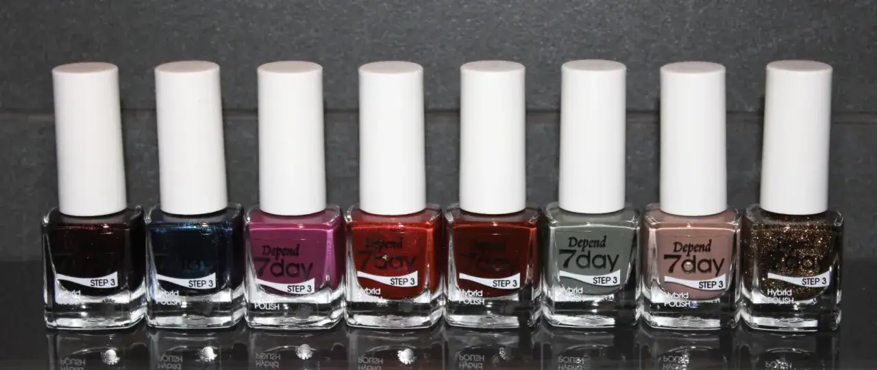 Rad med åtta olika färger av Depend 7day hybrid nagellack, från mörkt vinrött till glittrigt guld.