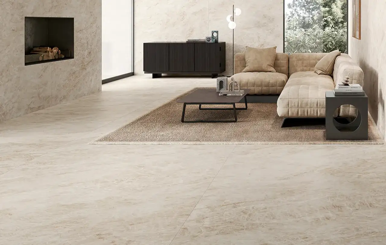Soggiorno moderno con camino, divano beige e pavimenti innovativi per interni con finitura effetto marmo chiaro.