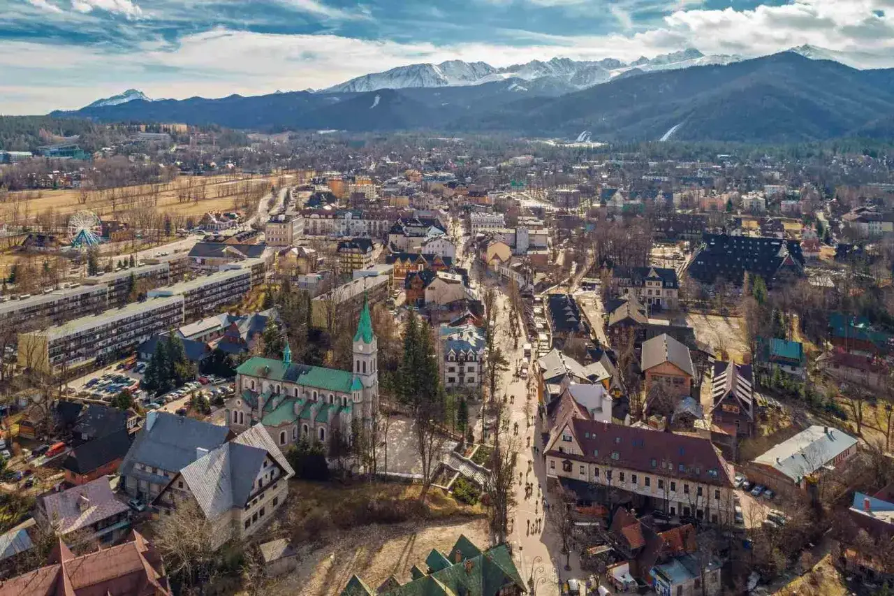 Widok na miasto z górami w tle. Zbliżamy się do Zakopanego, podróżując z Krakowa.