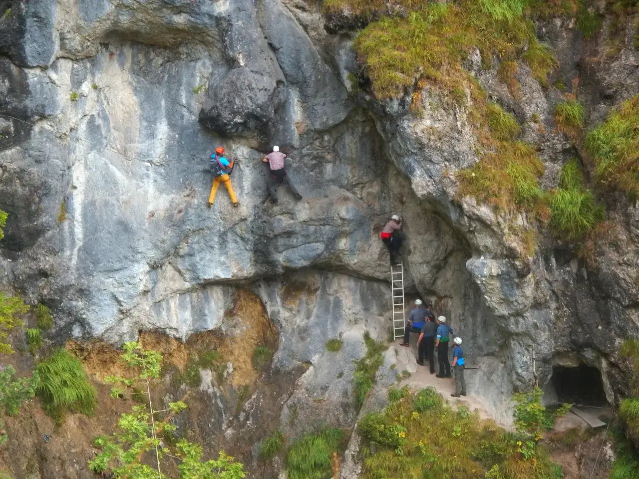 Kletterer am Hausbachfall Klettersteig erklimmen die Felswand, während eine Gruppe am Einstieg wartet.