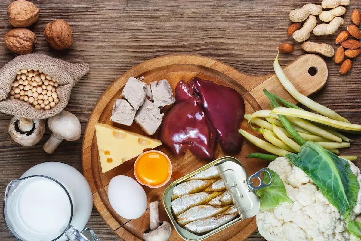 Assortiment d'aliments riches en vitamine B7 : foie, levure, œufs, sardines, noix, amandes, haricots, chou-fleur, champignons, fromage, lait et soja.
