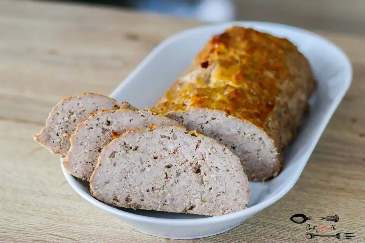 Pokrojona pieczeń z mięsa mielonego, apetyczna i soczysta, podana na białej paterze. Idealna na obiad.