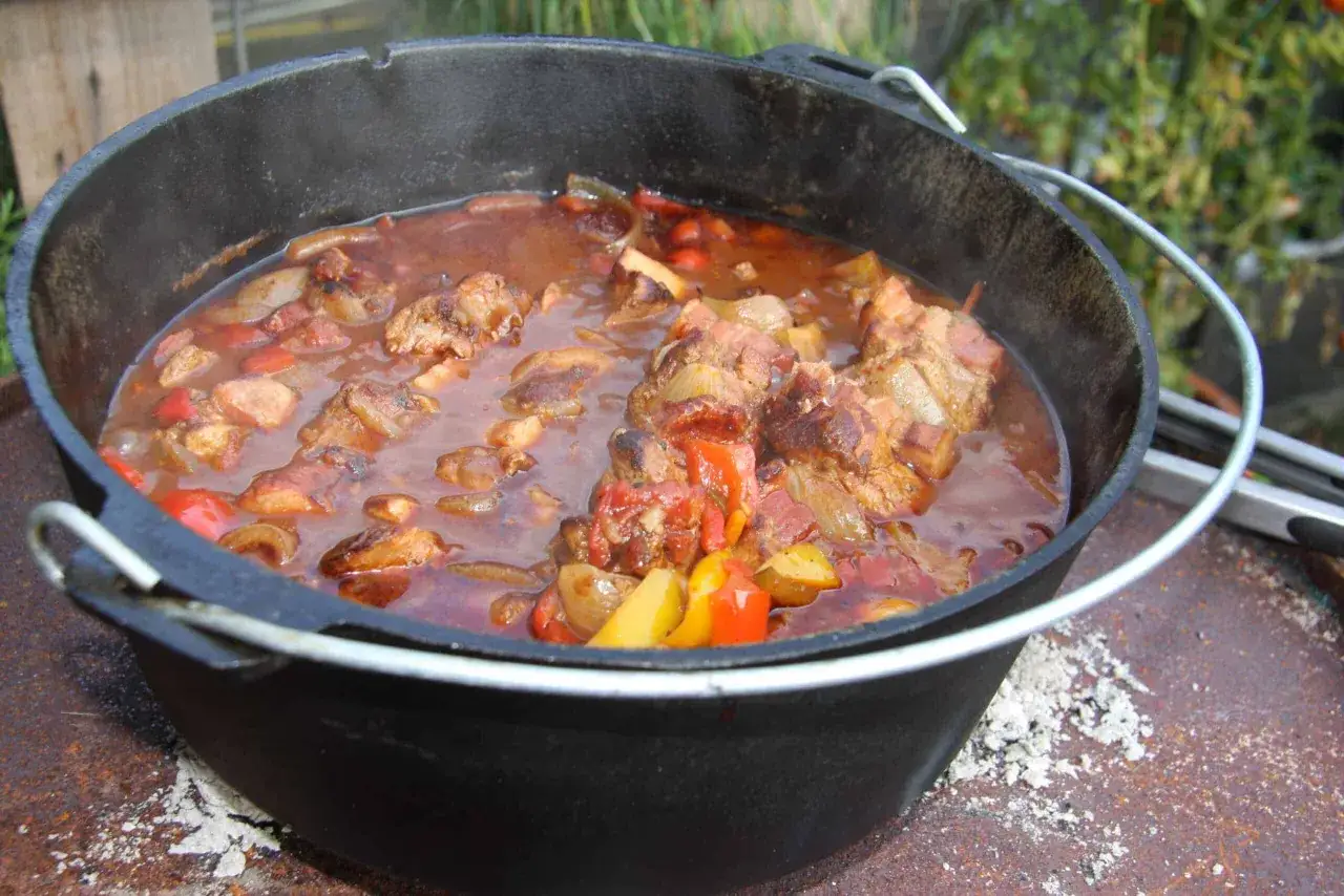 Herzhaftes Schaschlik mit Fleisch, Zwiebeln und Paprika k&ouml;chelt in einem Dutch Oven &uuml;ber gl&uuml;hender Asche.