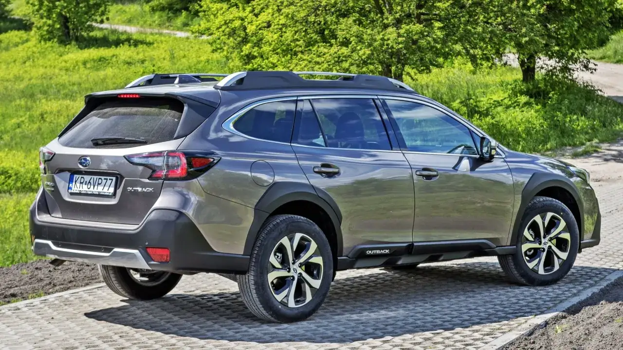 Szary Subaru Outback 2026 na tle zielonej trawy i drzew, gotowy na przygodę.
