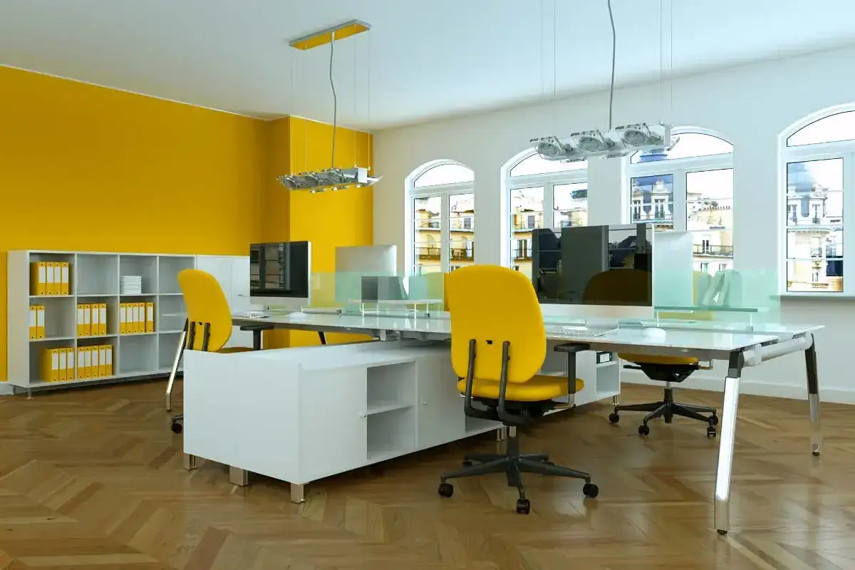 Bureau moderne avec mur jaune vif, mobilier blanc et chaises de bureau couleur jaune éclatant.