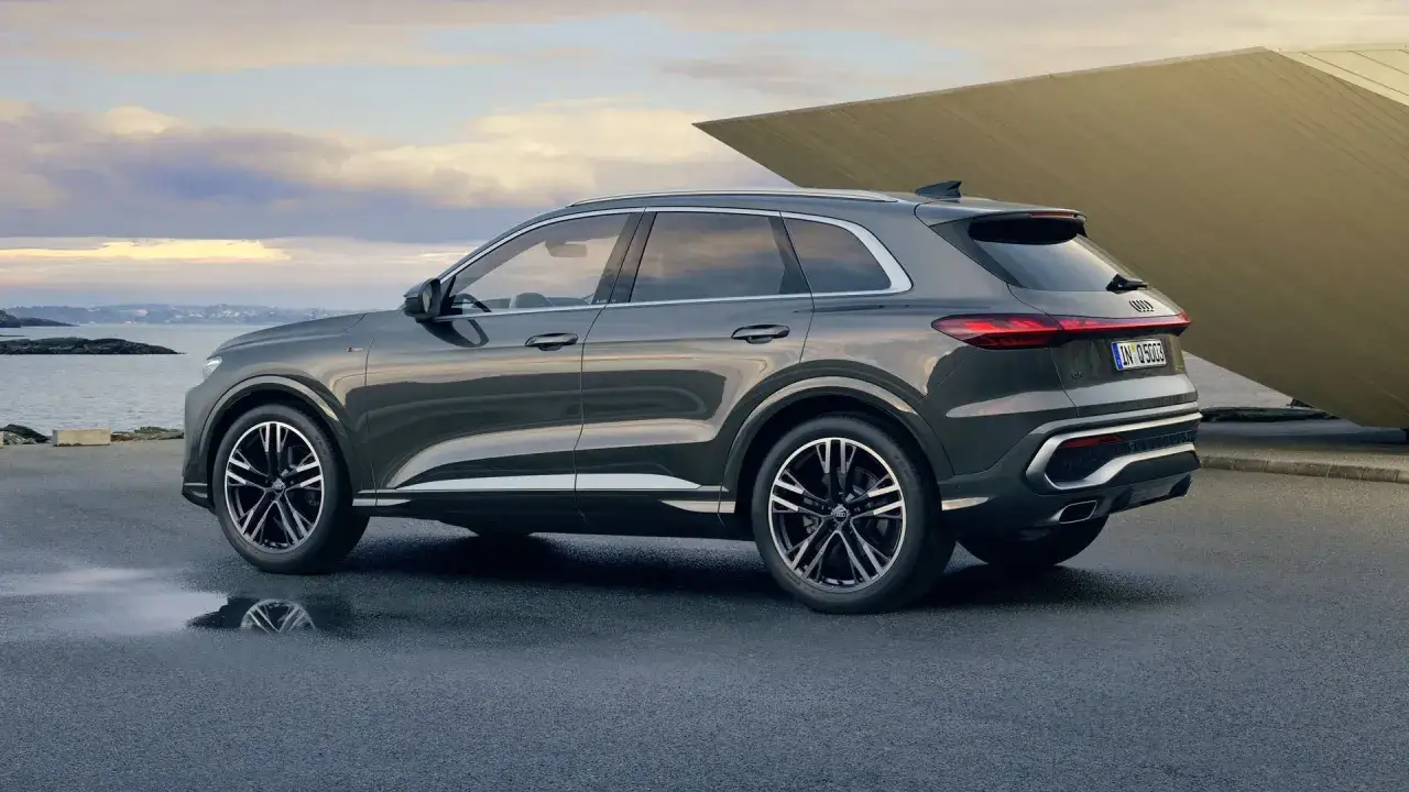 Elegancki Audi Q5 na tle nowoczesnej architektury i morza. Sprawdź audi q5 wymiary, by poznać jego gabaryty.