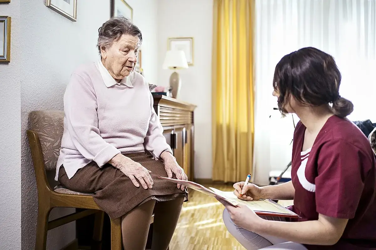 Ältere Dame spricht mit Pflegerin über einen Verschlechterungsantrag Pflegegrad.