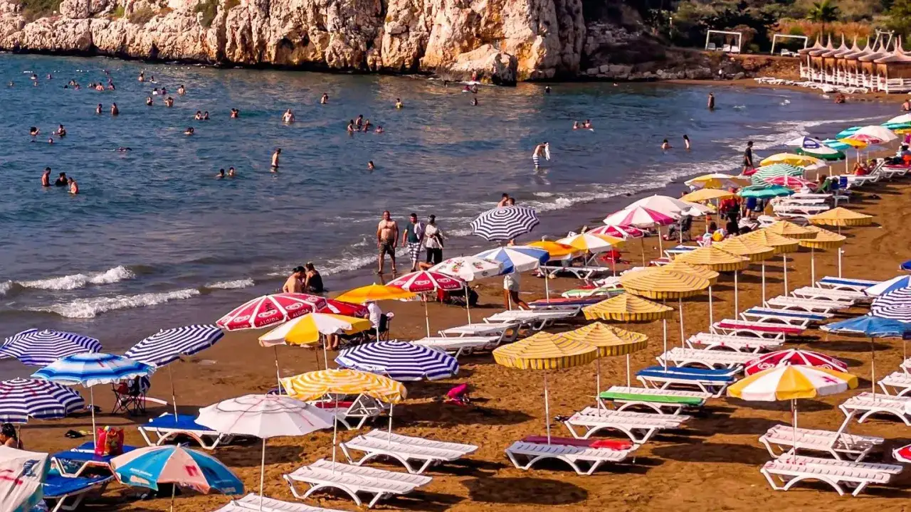 Tłum ludzi cieszy się słońcem i kąpielą w morzu na greckiej plaży. Czy w Grecji jest bezpiecznie? Wygląda na to, że tak, plaża jest pełna wypoczywających.