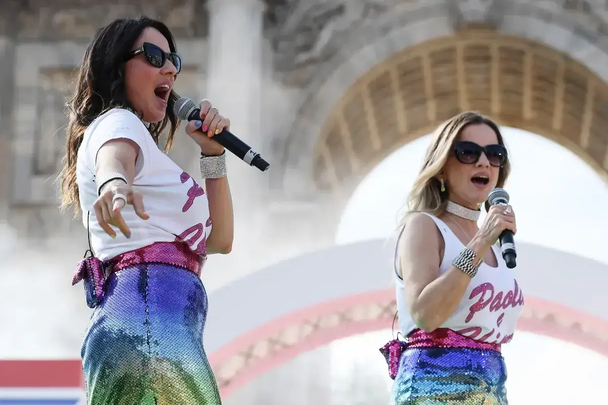 Le sorelle cantanti italiane, con paillettes arcobaleno e microfoni, incantano il pubblico con la loro energia.
