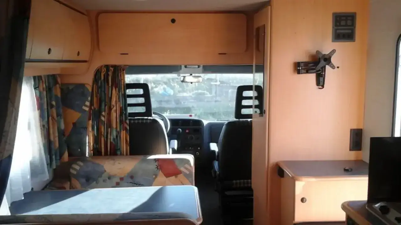 Intérieur d'un camping-car Challenger, prêt pour l'aventure. Les avis sur ce modèle sont nombreux, ici on voit le coin salon et la cabine de conduite.