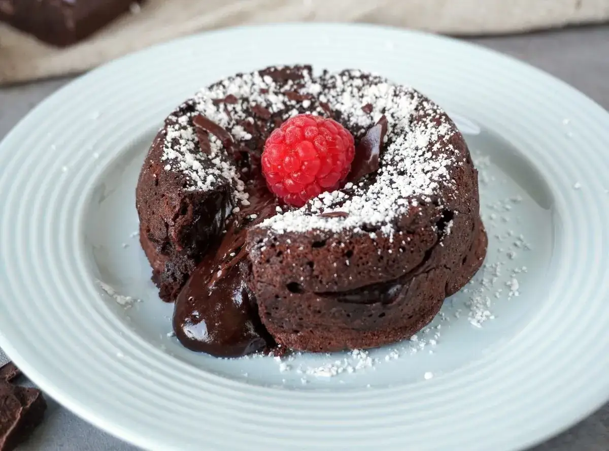 Schokoladen-Lava-Kuchen mit fl&uuml;ssigem Kern, best&auml;ubt mit Puderzucker und garniert mit einer Himbeere. Ein k&ouml;stliches Lava Cake Rezept.